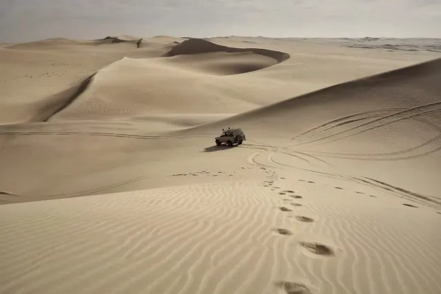 4x4 vehicle driving across sand dunes