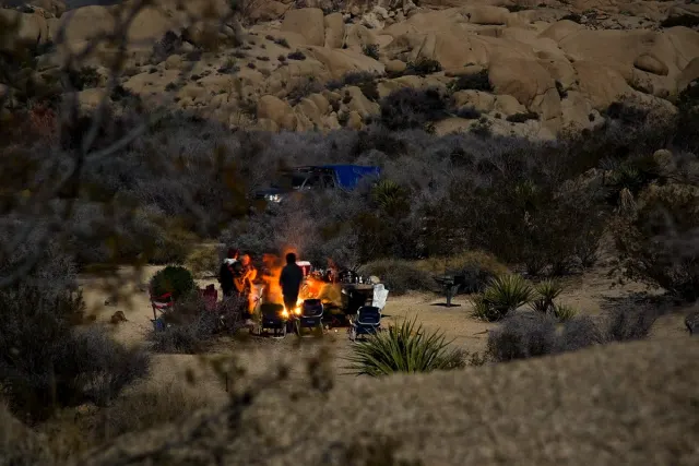 Group around a campfire at dusk at a desert camp