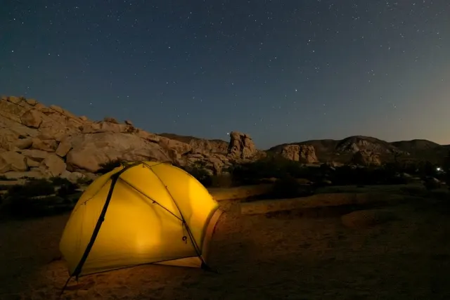 Lit tent at a desert camp under the stars